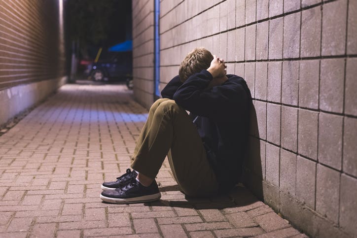 teenager sitting in the hallway with chronic illness