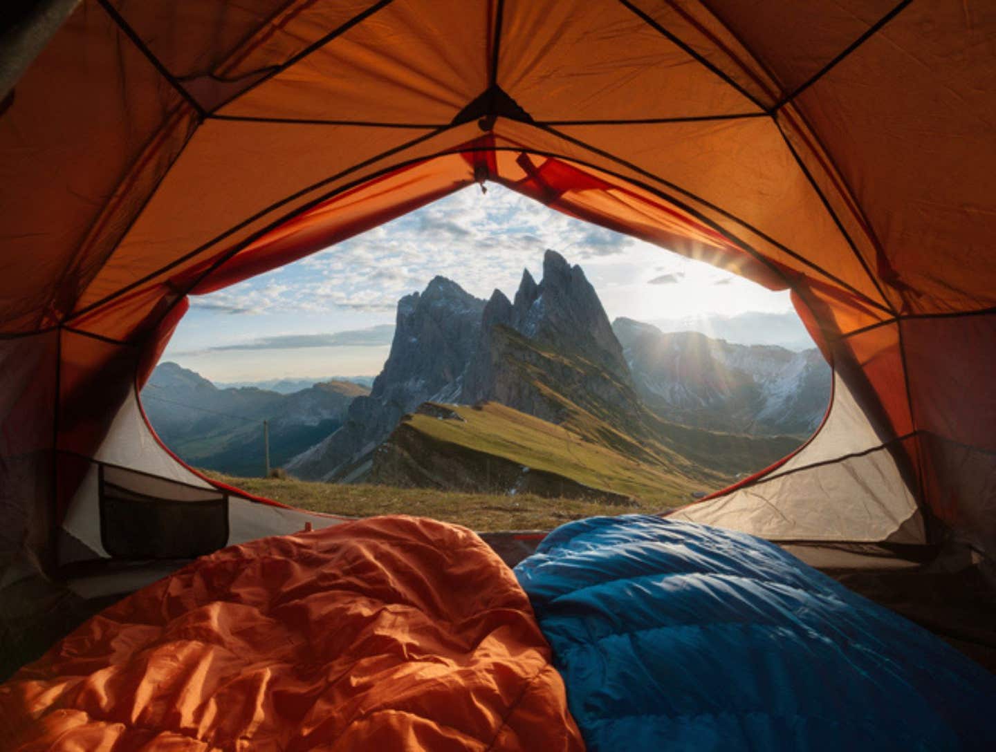 camping in orange tent with a view of a mountain