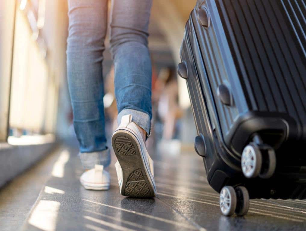 Woman traveler walking alone with suitcase bag. Travel weekend vacation trip (Airports Named America's Favorite)