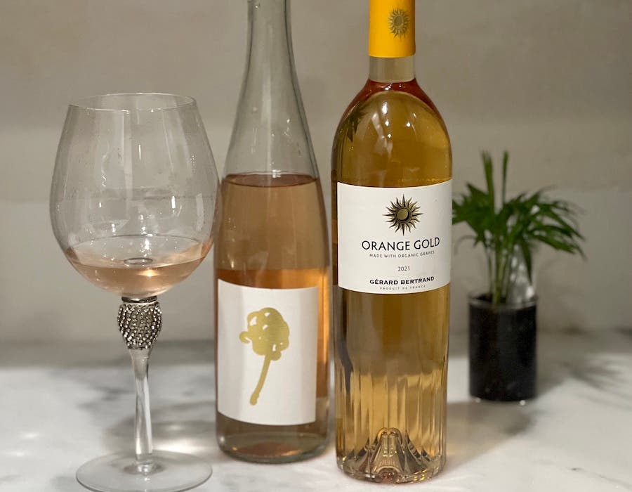 Bottles and a glass of orange wine on a counter