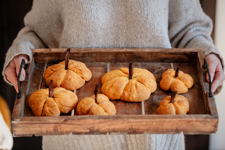 Woman hold desk with pumpkin cookies at kitchen. Halloween Food