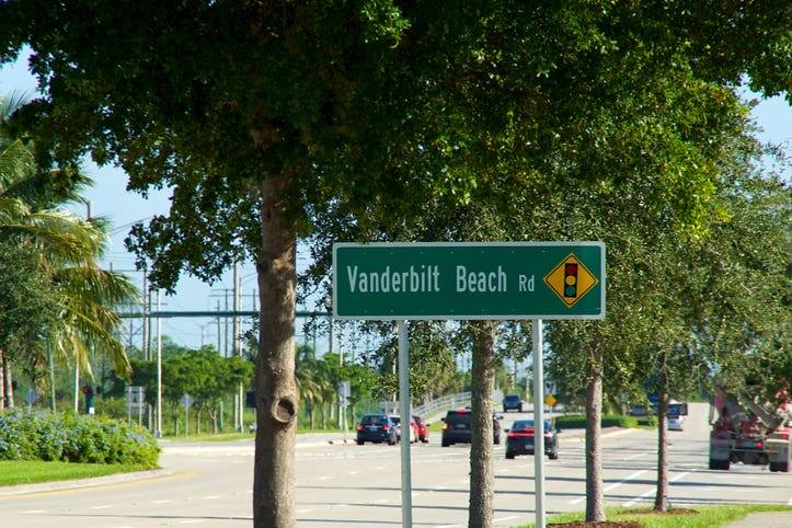 Vanderbilt Beach road sign with traffic near single family homes in Naples Florida