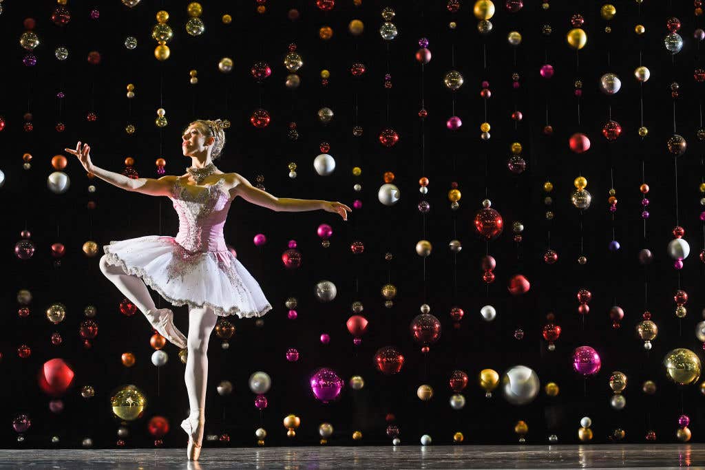 Dancer Constance Devernay, dressed in the sugar plum fairy costume poses against a backdrop of Christmas baubles