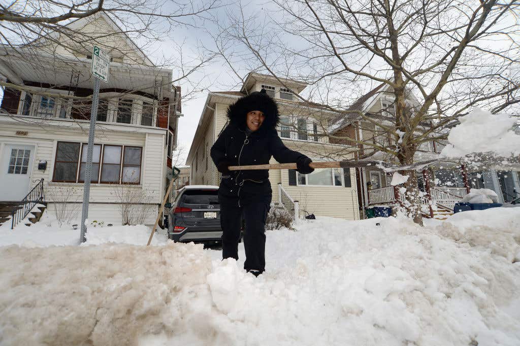 Woman shovels snow in Buffalo, the hottest housing market of 2024