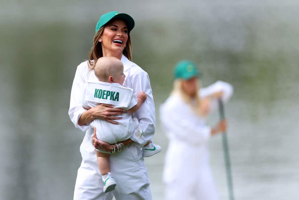 Brooks Koepka of the United States wife, Jena Sims, holds their son, Crew, during the Par Three Contest prior to the 2024 Masters