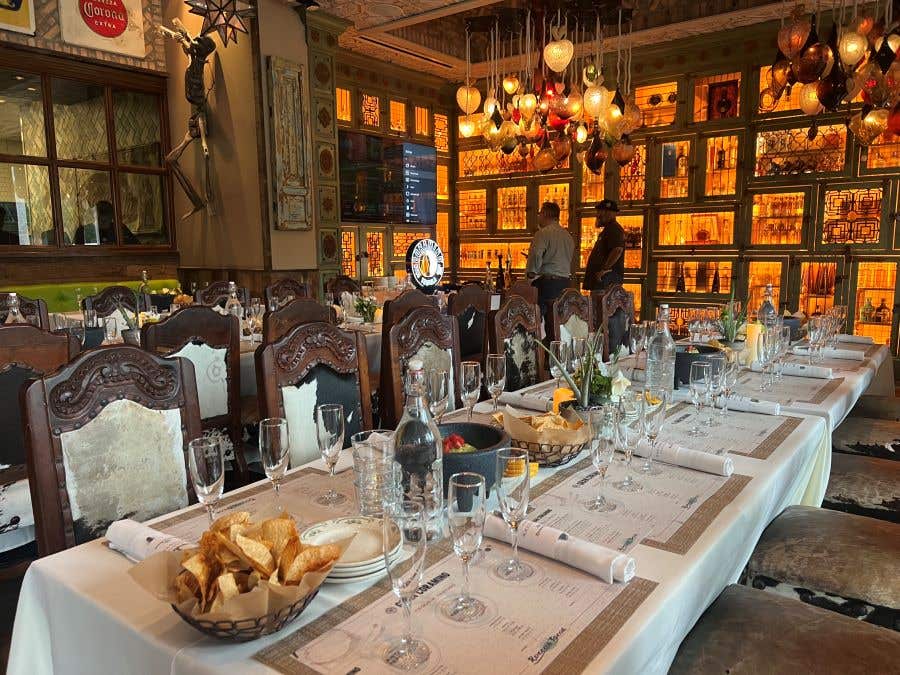 Long table, set with wine glasses, dishes and bowls of tortilla chips for Kevin Hart Tequila Dinner In Naples