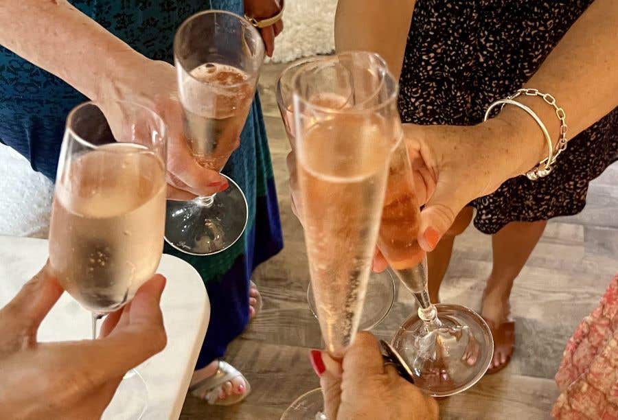 Four wine and Champagne glasses full of pink wine, clinking together for rose day soiree