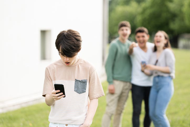 Teenager boy looking at phone and suffering cyber bullying.