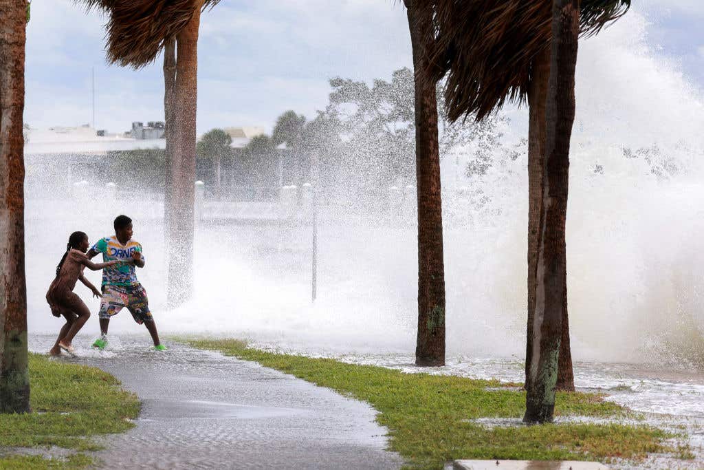 People are splashed by churning surf from Tampa Bay as Hurricane Helene passes offshore on September 26, 2024, in St. Petersburg, Florida. Helene is forecast to become a major hurricane, bringing the potential for deadly storm surges, flooding rain, and destructive hurricane-force winds along parts of the Florida West Coast. A hurricane direct hit is possible with the next storm