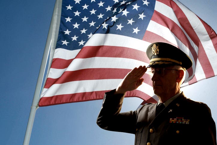 Silhouette of veteran US Army Colonel Chaplain wearing hat and saluting with an American flag flying behind him.