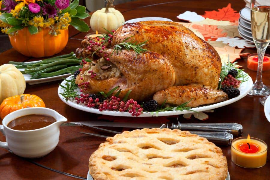 Table set with lots of food, a big turkey in the center for Thanksgiving travel from RSW i