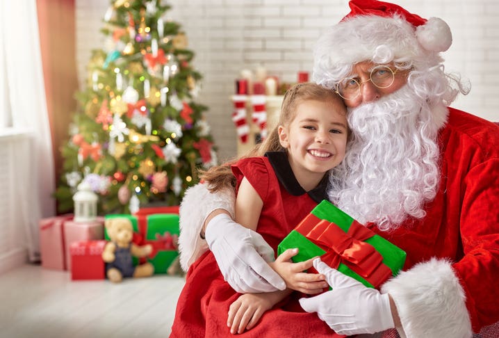 Santa Claus giving a present to a little cute girl. Photos with Santa