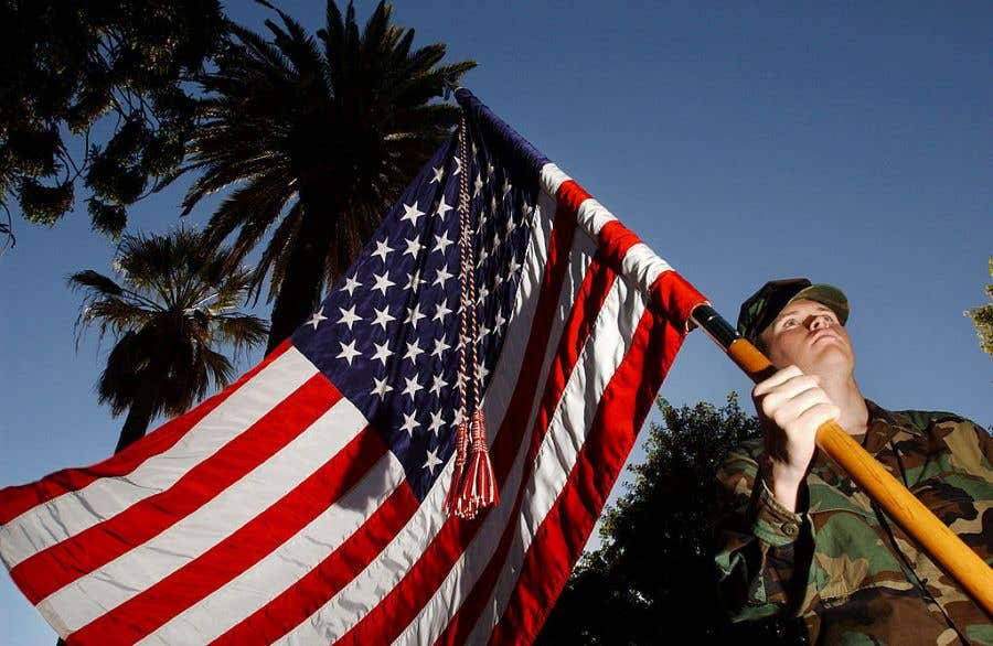 Man in uniform holding an American Flag with palm trees in background for Veterans Day Weekend in Southwest Florida