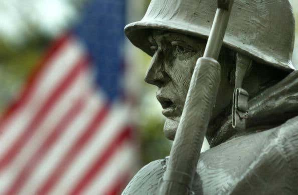 An American flag flies at half staff near a statue of a soldier at the Korean War Memorial on Veterans Day November 11, 2002 in Washington, DC.