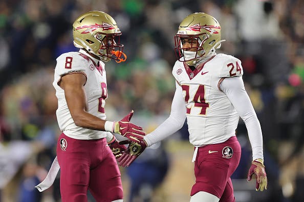 Azareye'h Thomas #8 and K.J. Kirkland #24 of the Florida State Seminoles celebrate a tackle