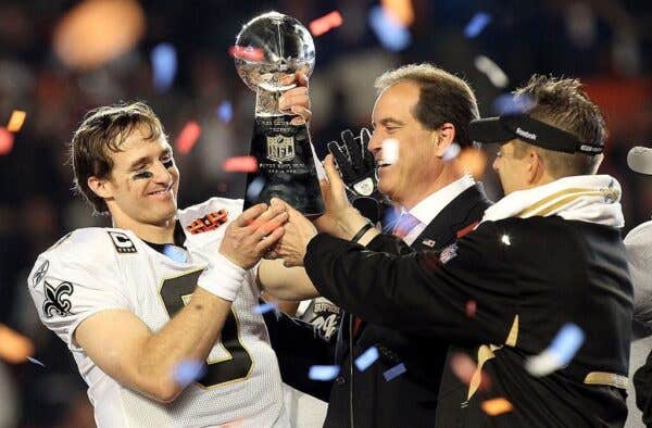 Head coach Sean Payton of the New Orleans Saints passes quarterback Drew Brees #9 the Vince Lombardi trophy after defeating the Indianapolis Colts during Super Bowl XLIV on February 7, 2010 at Sun Life Stadium in Miami Gardens, Florida.