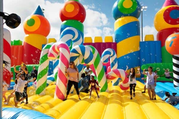 Giant inflatable castle and candy canes in bright colors with kids jumping in the middle for SWFL Weekend Fun