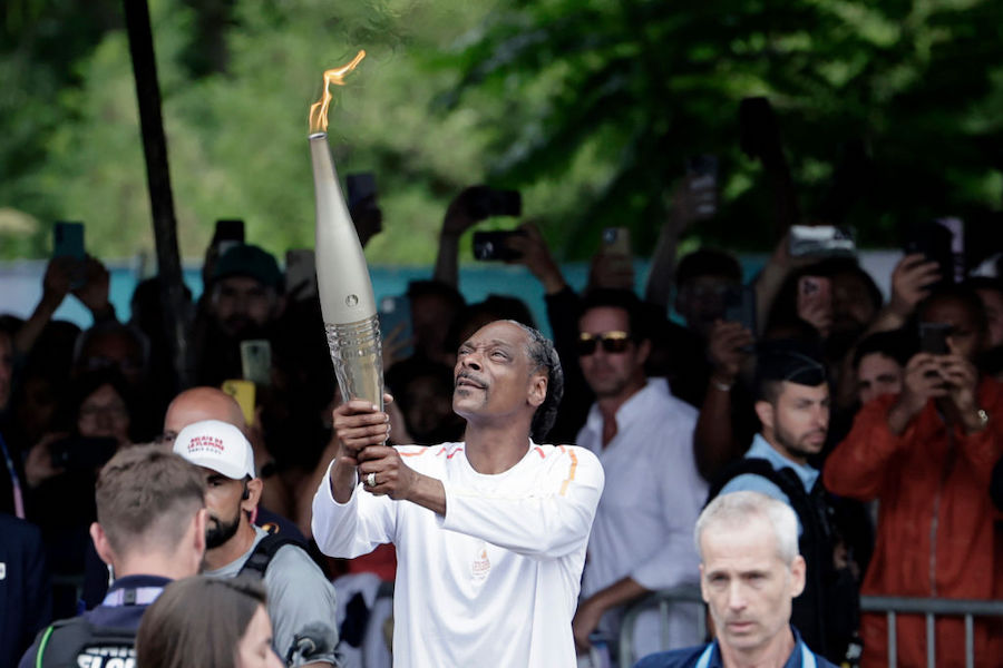 Snoop Dogg, dressed in white, carrying the Olympic Torch. One of the 5 Snoop Dogg moments from the Olympics